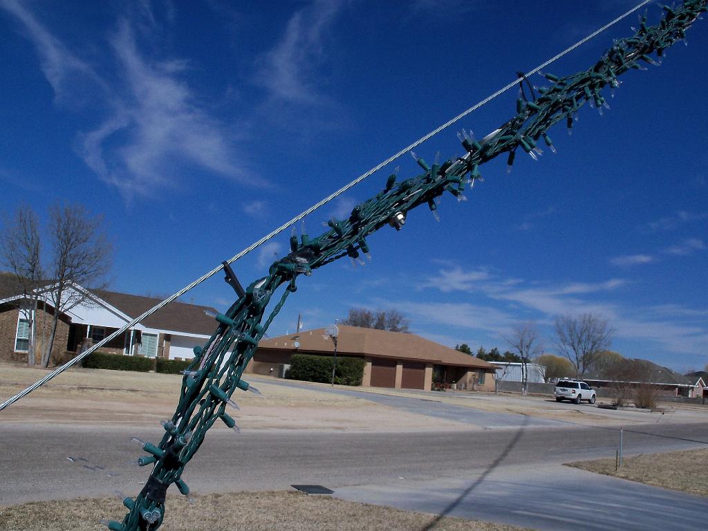 100_0478.JPG - How the 'Beam of Light' is made. The 100' 'Beam' is two 50' sections. One has a wiring harness going on down, and one going up to the tower. Each has a wiring harness and 3/16" guy line in the center. Each 3' long channel is a 100ct string of mini's, zip tied back and forth, and connected the the wiring harness. Then the complete assbly is pulled up to the tower and zip-tied to the 'real' 3/16" guy wire. (I left it loose so it would slide and so the bulbs wouldn't be too tight against the 'real' guy wire.)